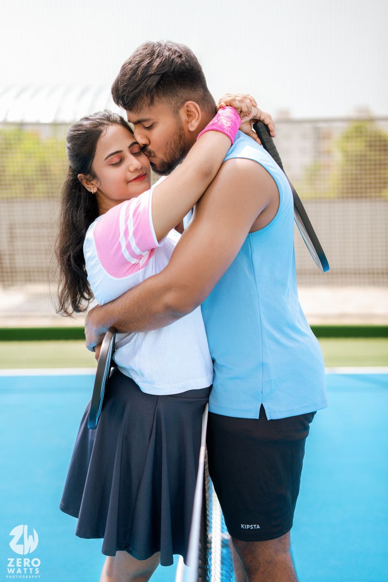 Couple sharing an intimate embrace on a pickleball court wearing matching athletic wear.
