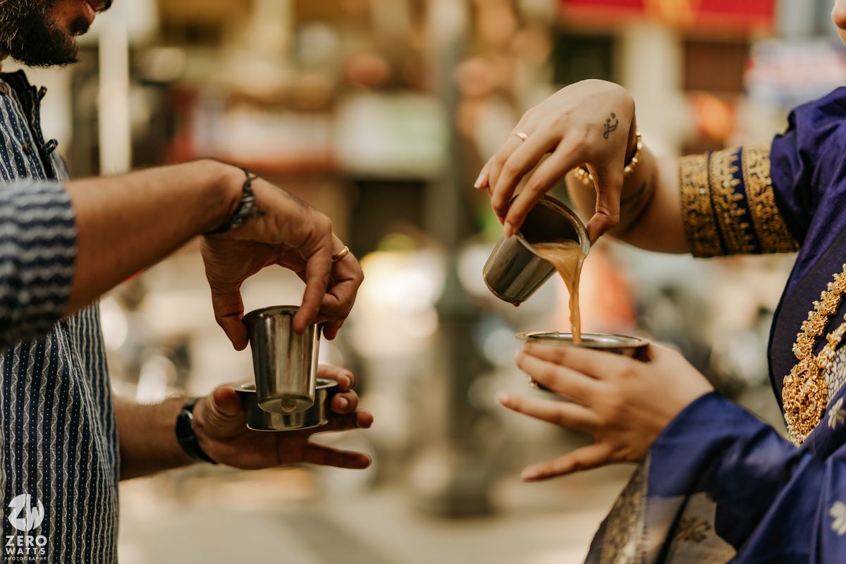 Hands pouring drip coffee using a gooseneck kettle into brewing equipment with a blurred background.