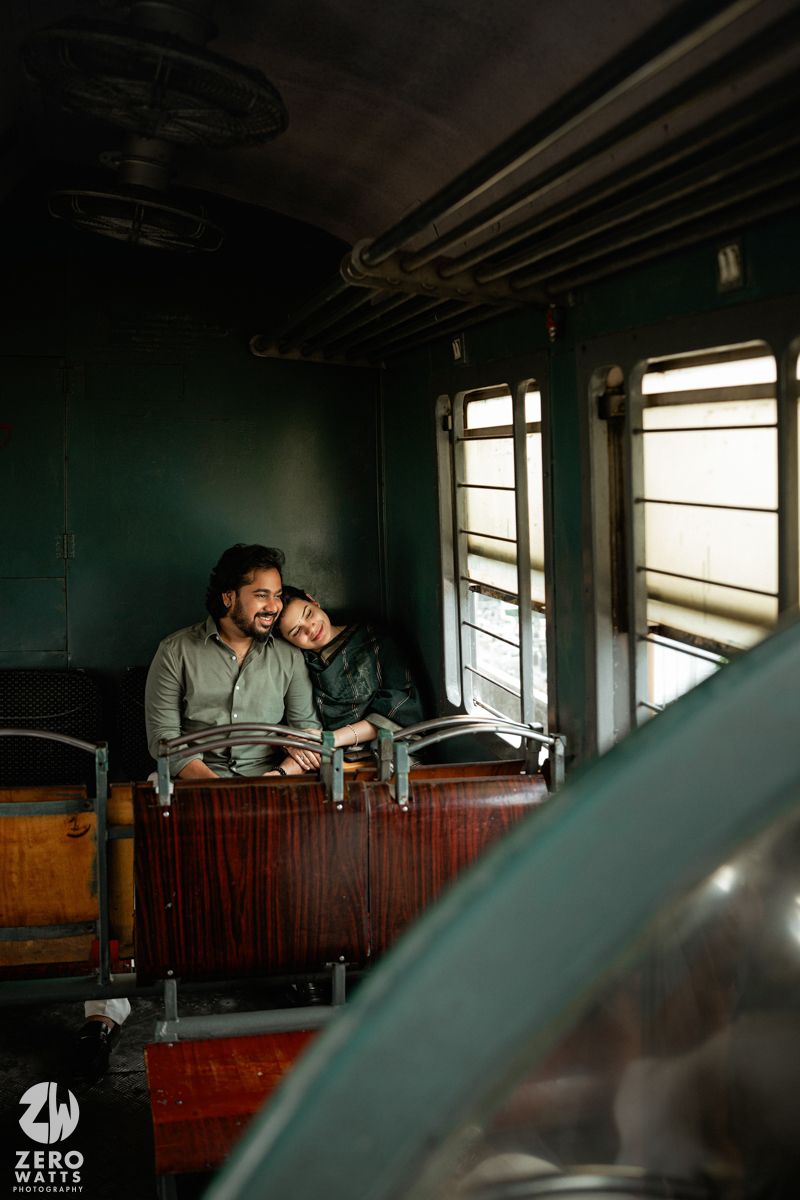 Couple enjoying romantic moments by window in vintage train interior with wooden seats.