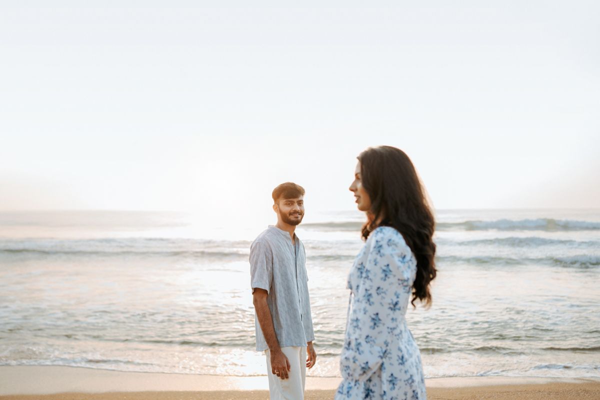 Couple in light clothing having romantic moment on beach at sunset.