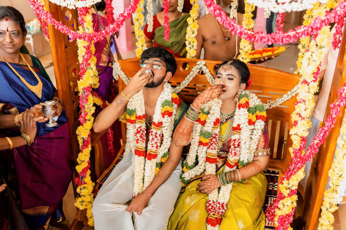 A traditional South Indian wedding ceremony with flower garlands and decorations in vibrant pink and yellow colors.