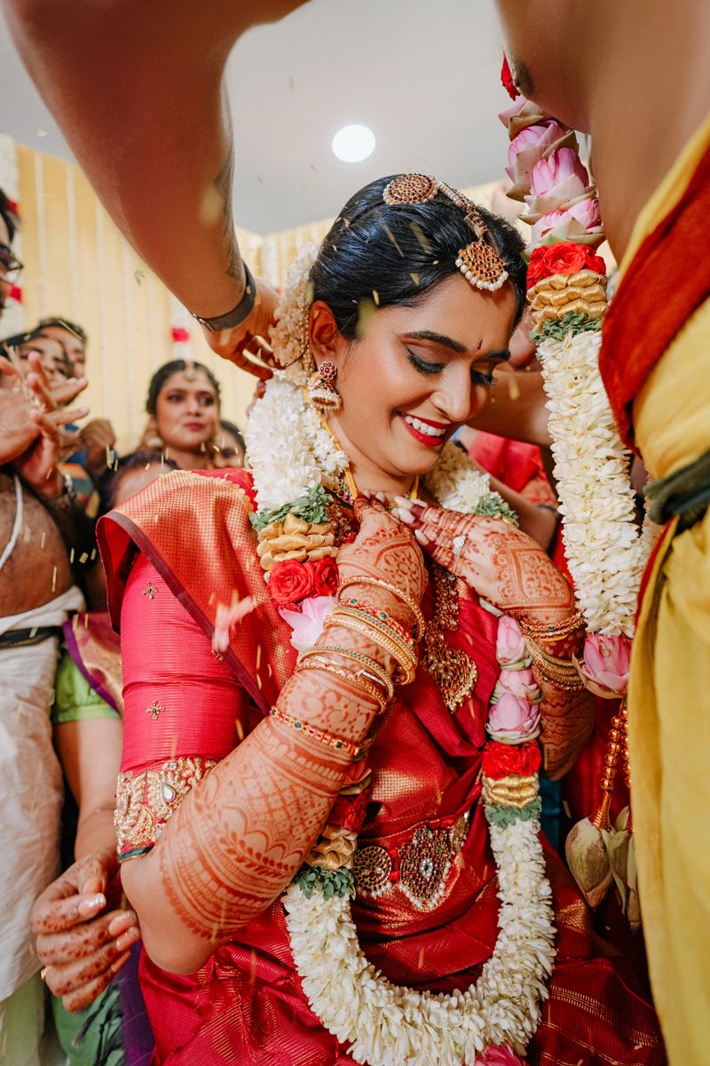 Traditional wedding ceremony with ornate decorations and floral garlands in vibrant red and gold colors.