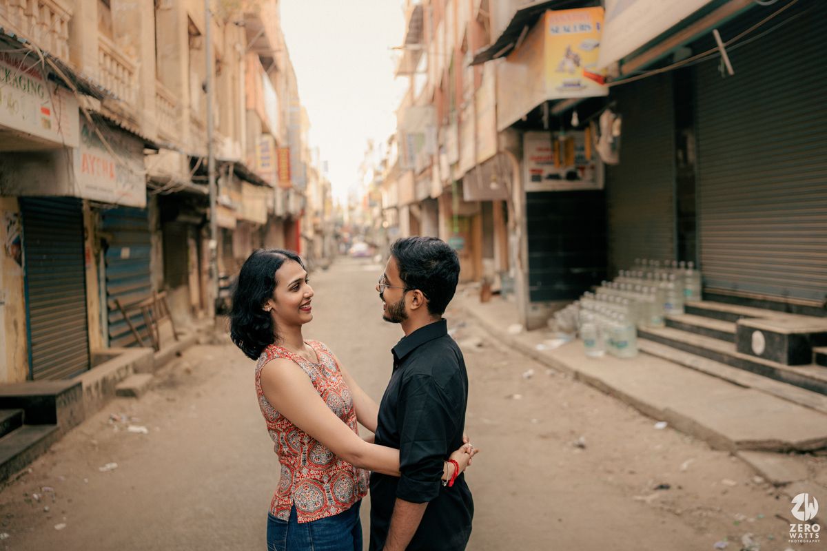 Couple sharing intimate moment while standing in empty urban alley with historic buildings.