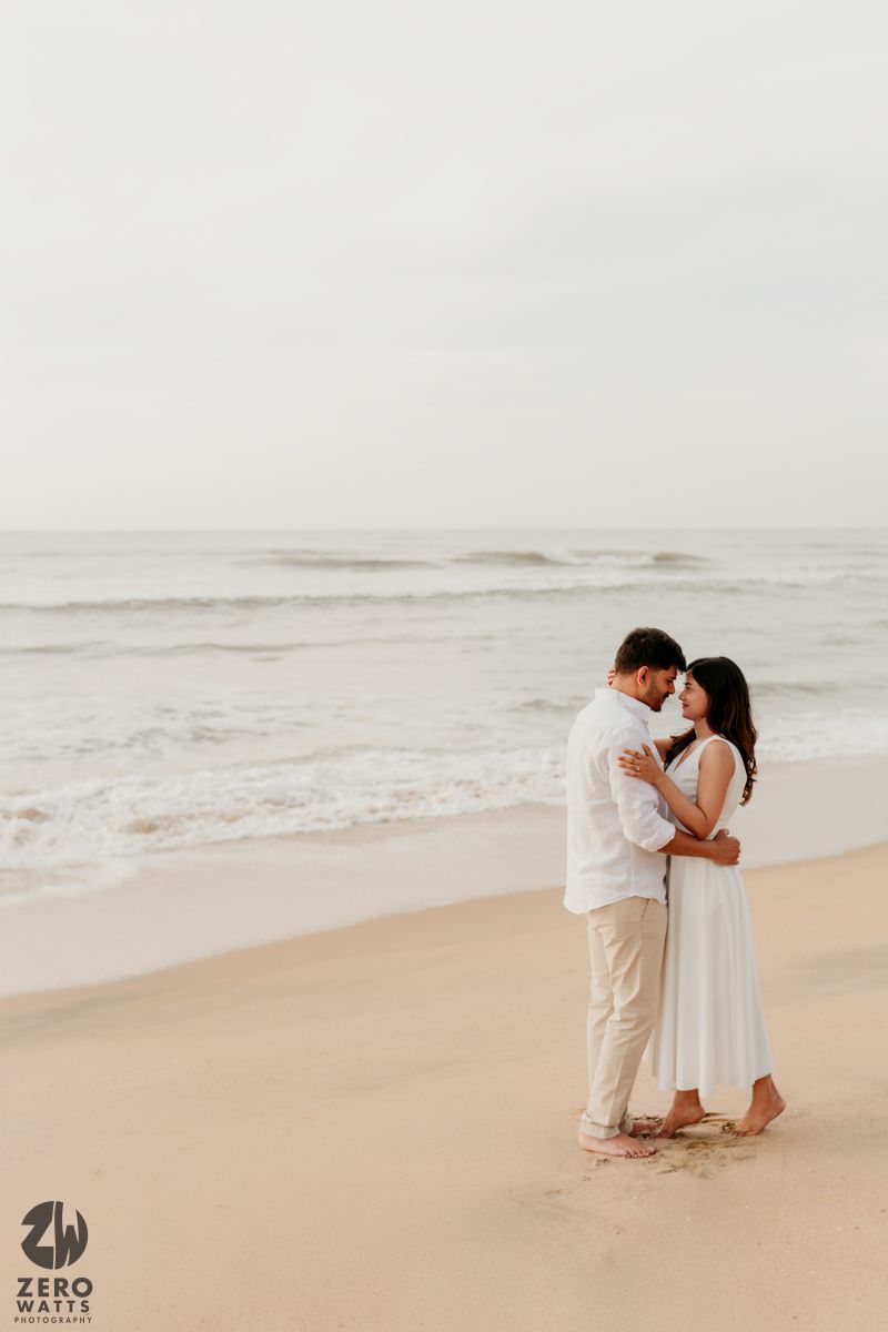 A romantic couple embraces on a misty beach shore during an intimate photoshoot.