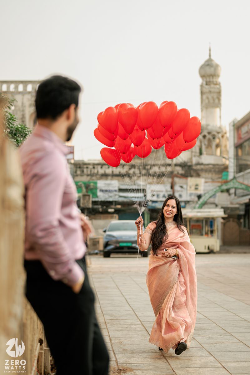 A romantic scene with red heart balloons against historic architectural backdrop.