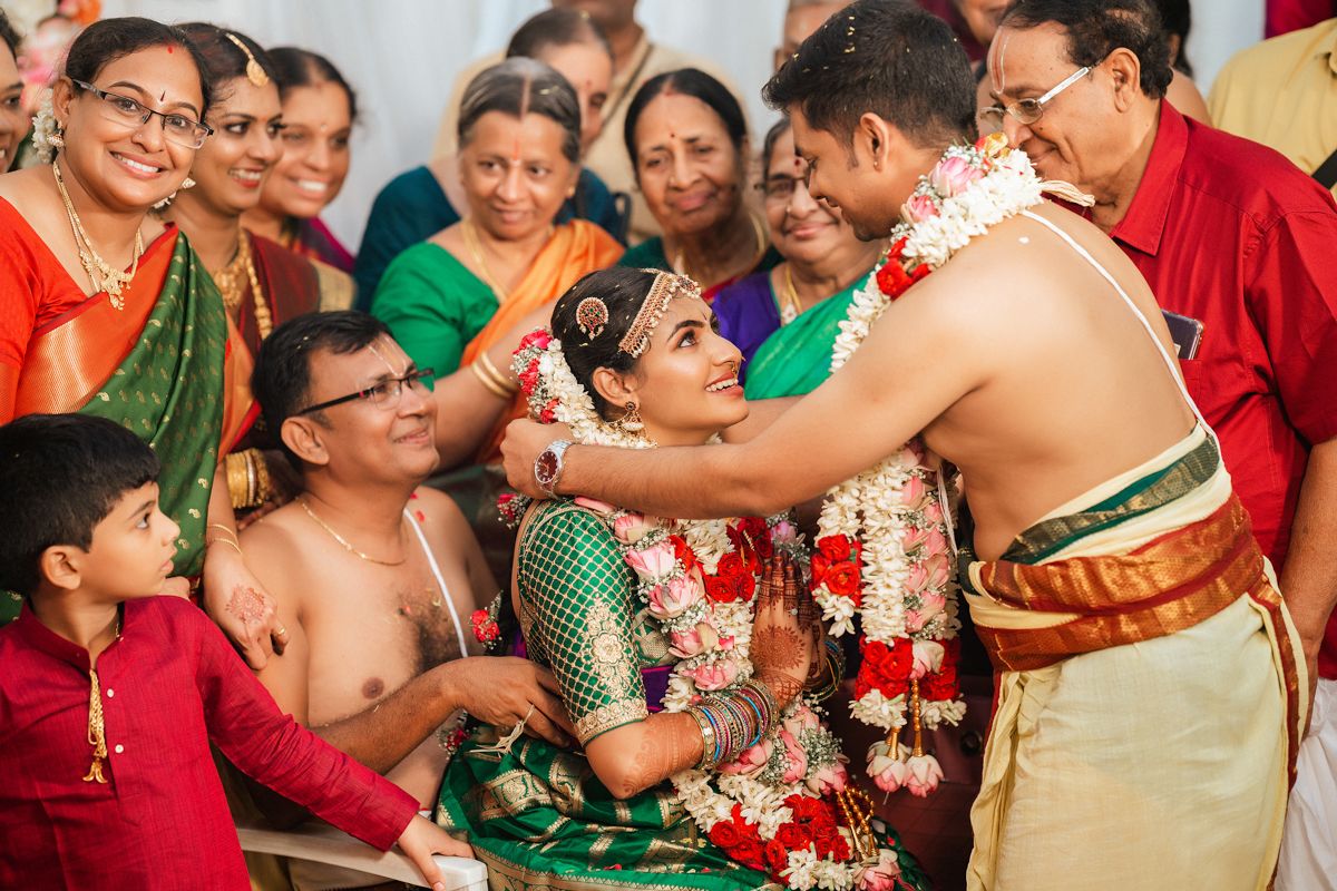 Traditional South Indian wedding ceremony with family gathered around as rituals are performed with garlands.