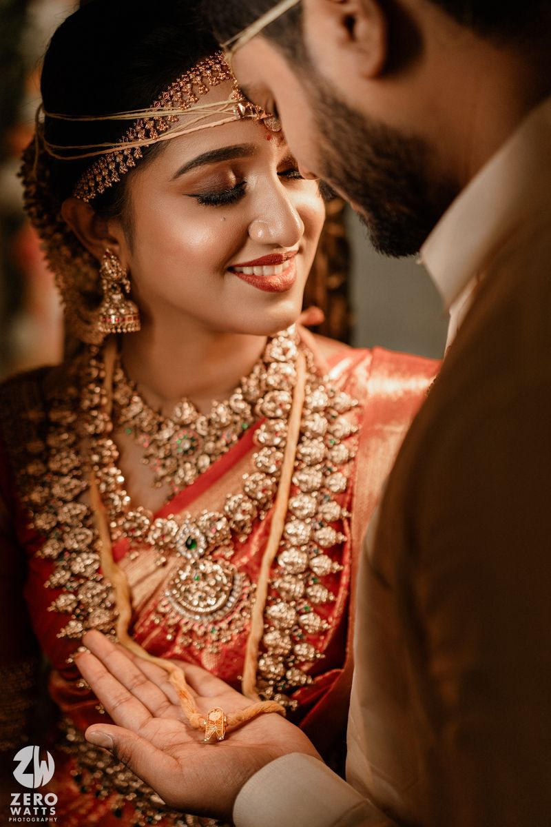 Close-up photography showcasing intricate bridal jewelry and traditional red attire during an Indian wedding celebration.