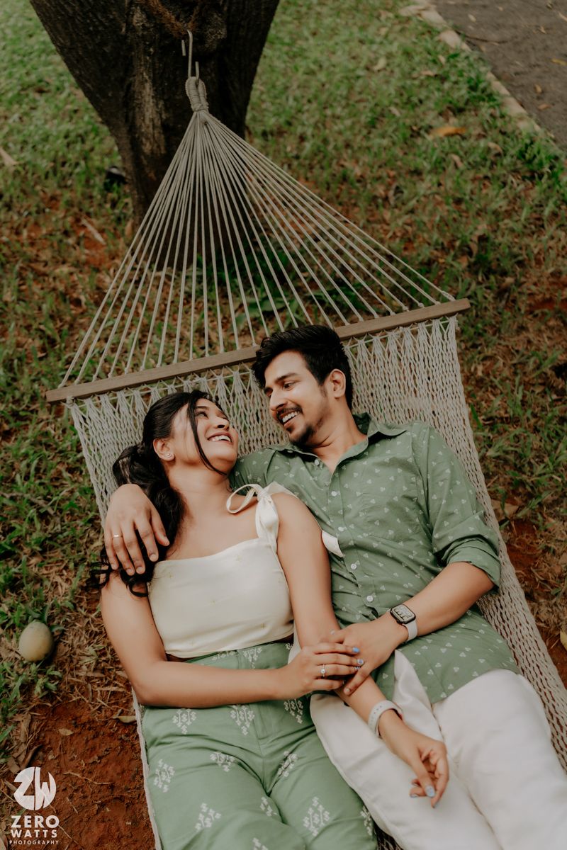 A couple relaxes together in a comfortable hammock surrounded by greenery in an intimate outdoor setting.