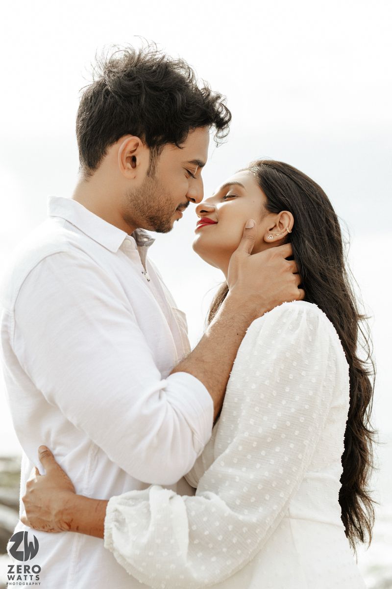 A romantic portrait of a couple in white embracing closely outdoors.