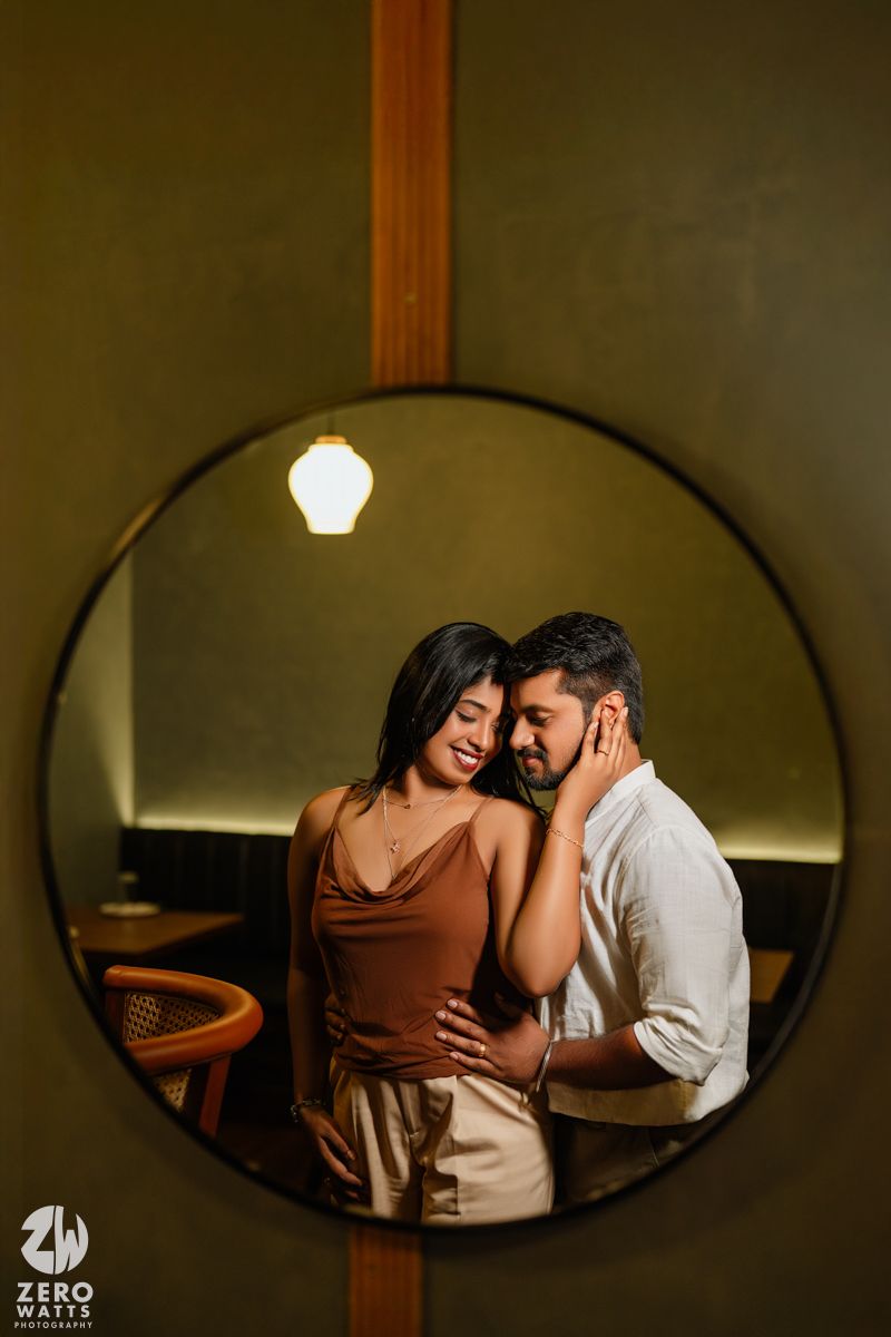 Intimate couple portraits reflected in oval mirror with moody lighting.
