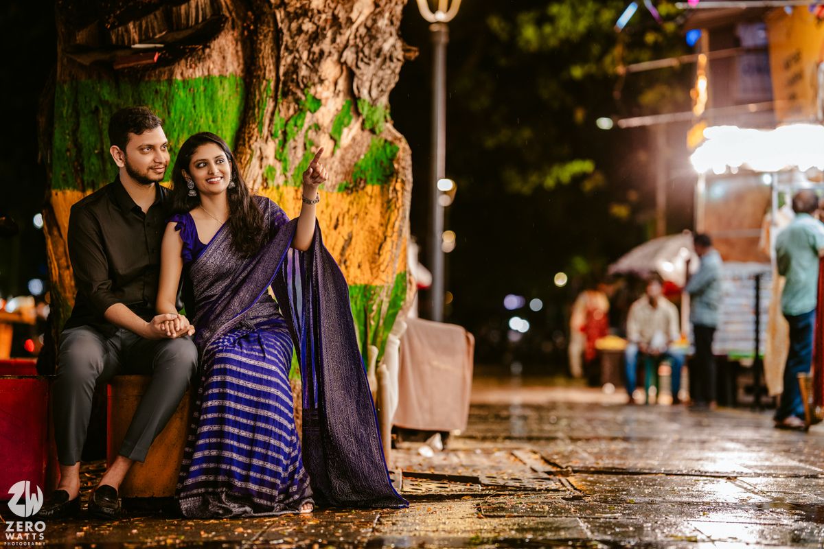 A couple sitting on street bench at night with colorful illuminated backdrop.