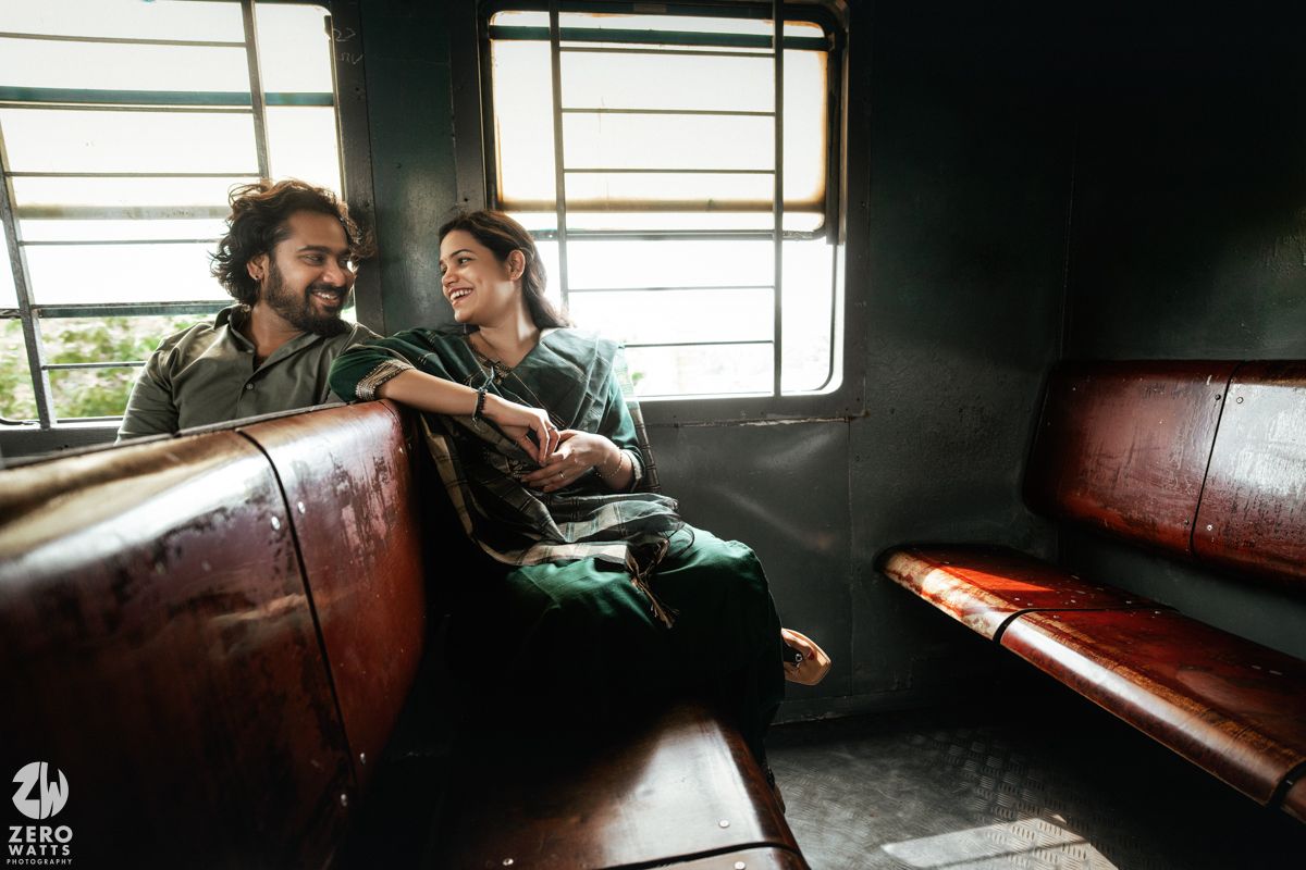 A couple sits close together on vintage train seats during a romantic journey.
