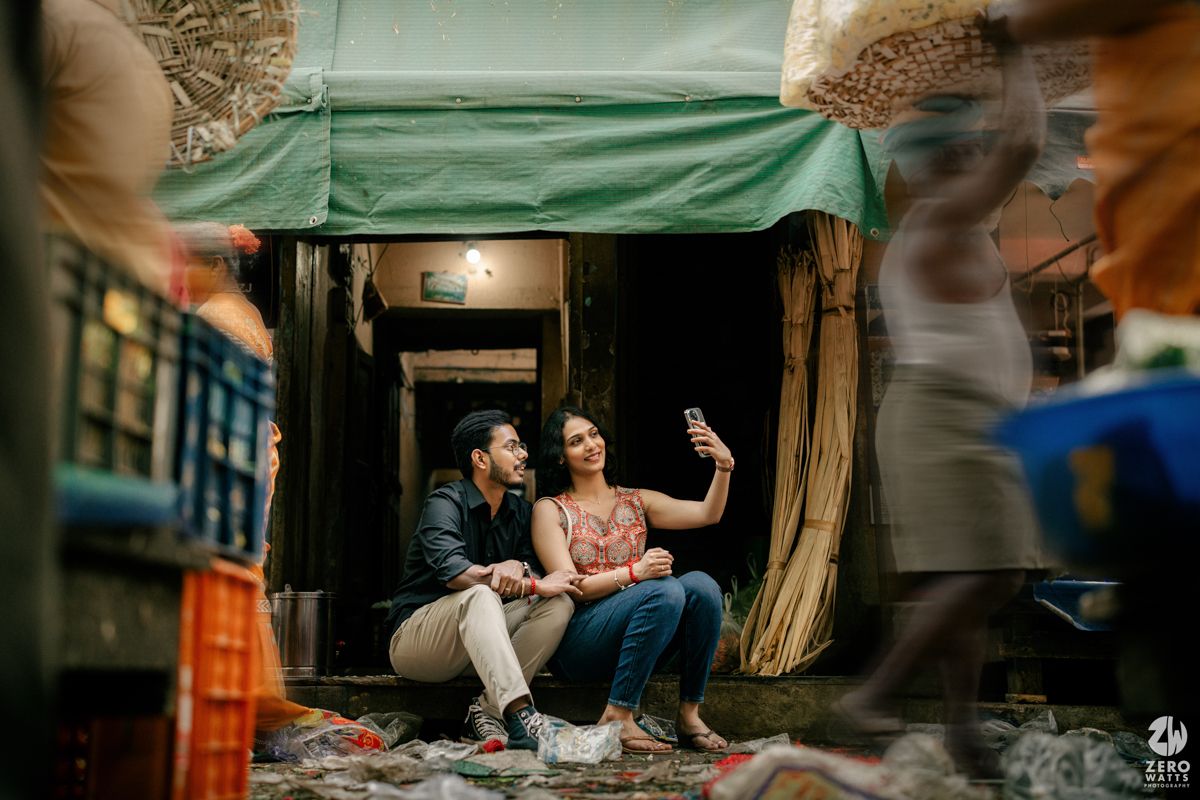 A couple enjoys a candid moment under a green awning in an urban alleyway setting.