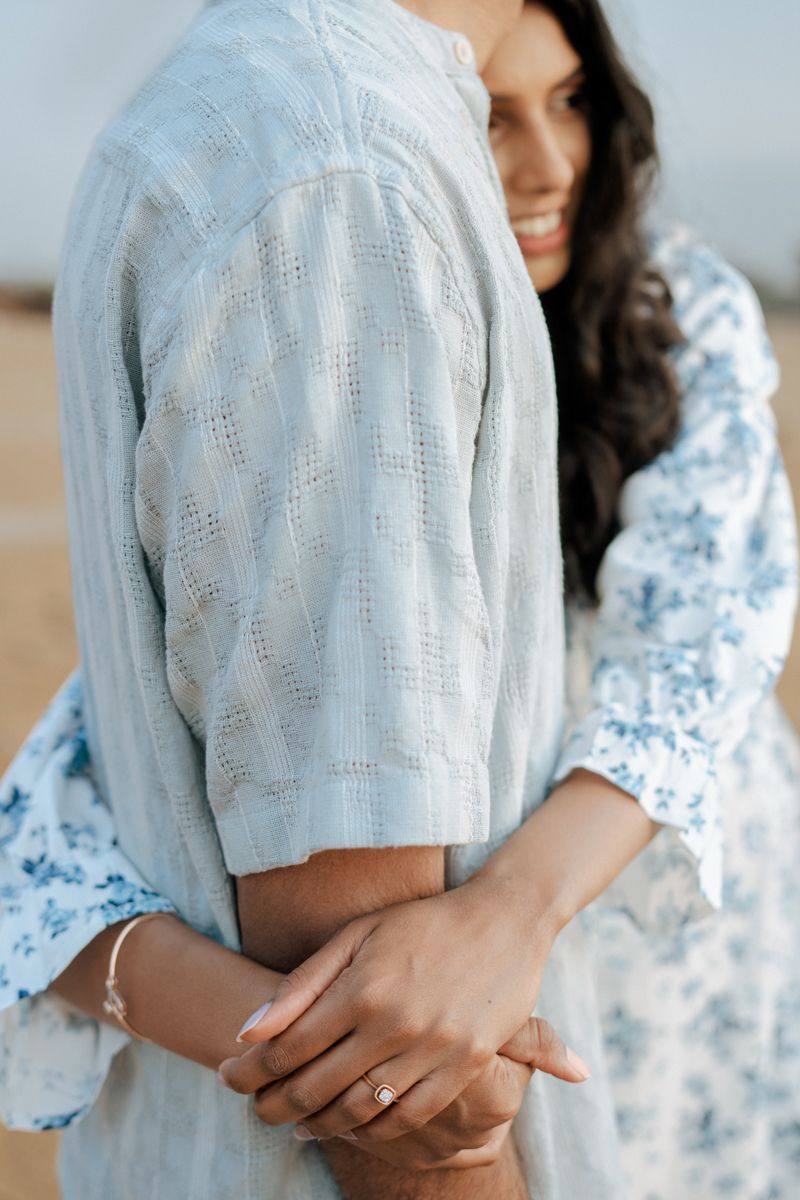 An intimate close-up of hands touching while wearing soft blue and floral patterned clothing.