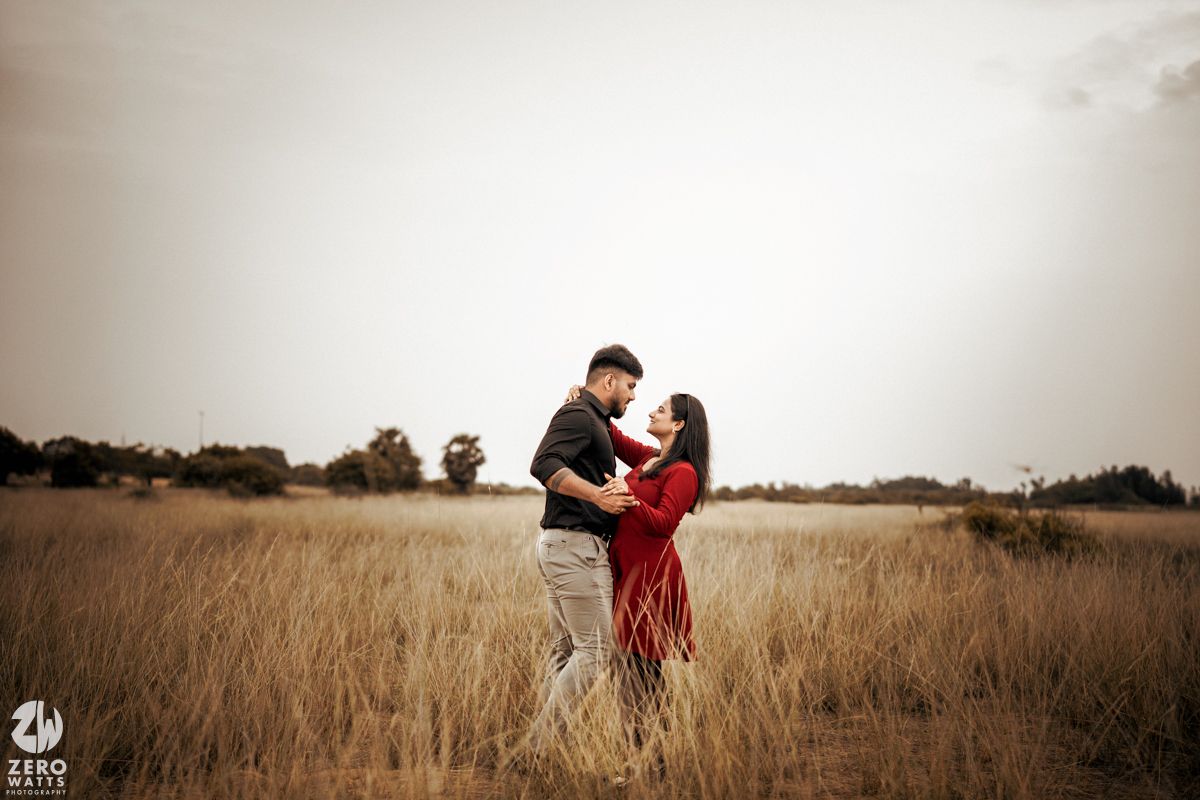 Romantic couple embracing in a sunlit field of tall wheat grass.