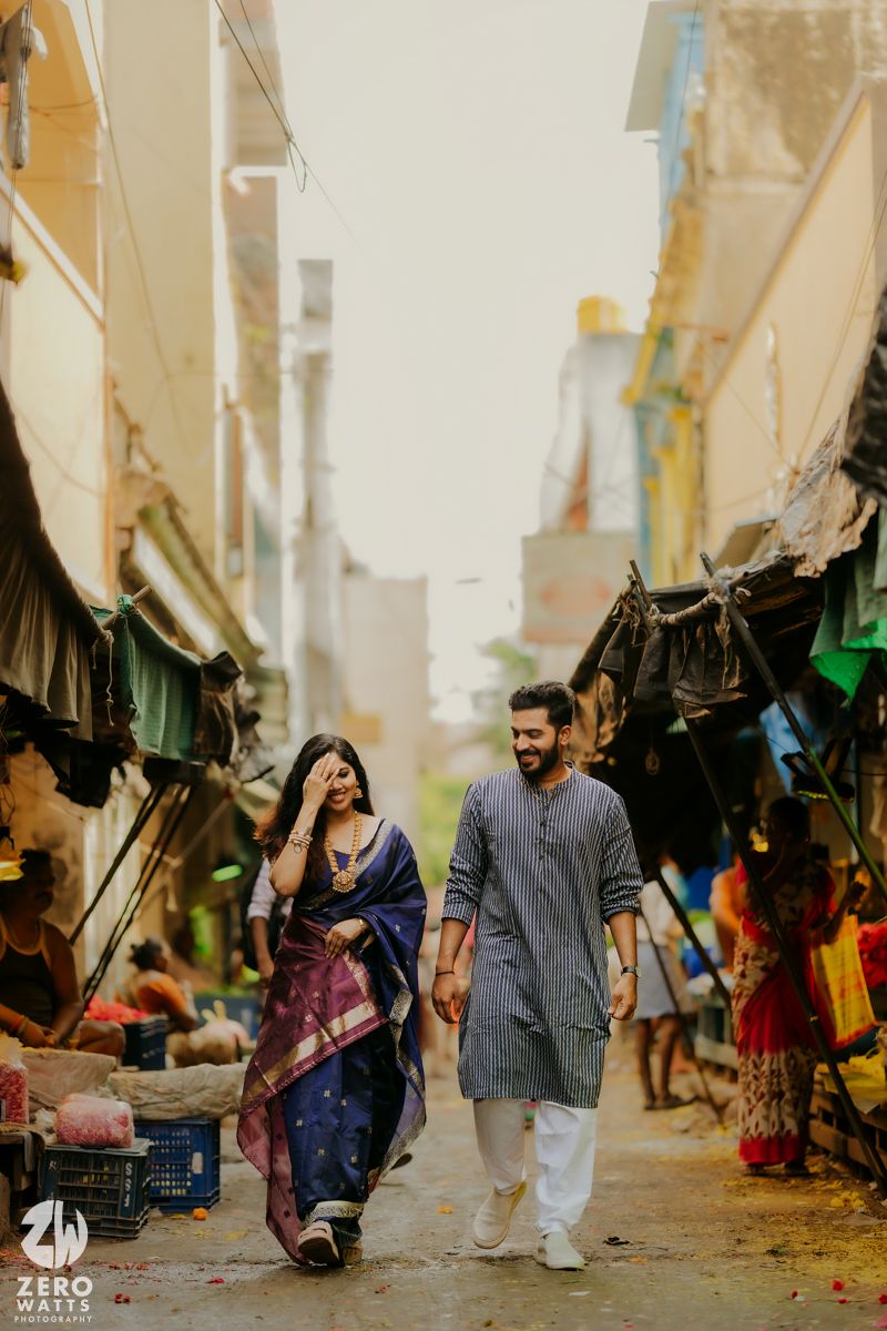 A bustling outdoor bazaar or street market with vendors and shoppers under canopies and tents along a narrow alley.