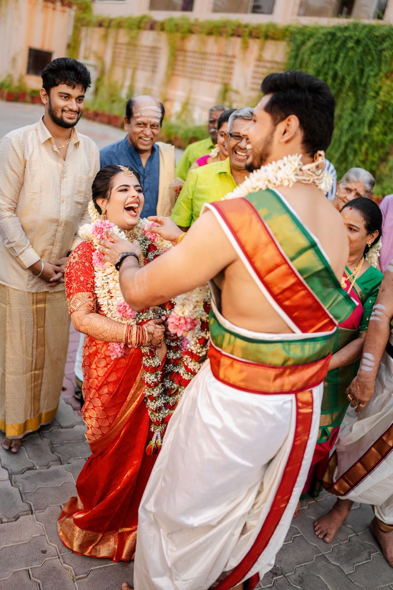 Couple in traditional South Indian wedding attire sharing a joyful moment during ceremony celebrations.