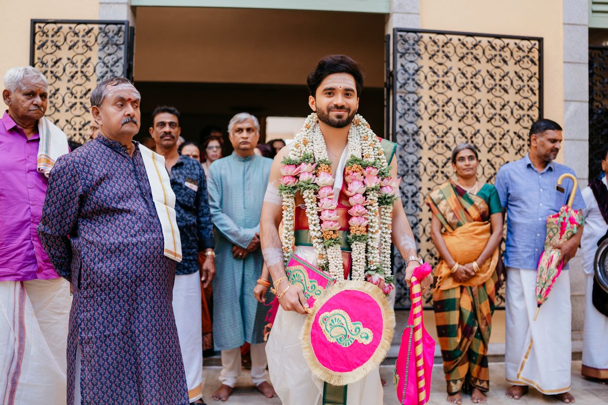 A groom in traditional Indian attire stands with family members during a wedding ceremony.