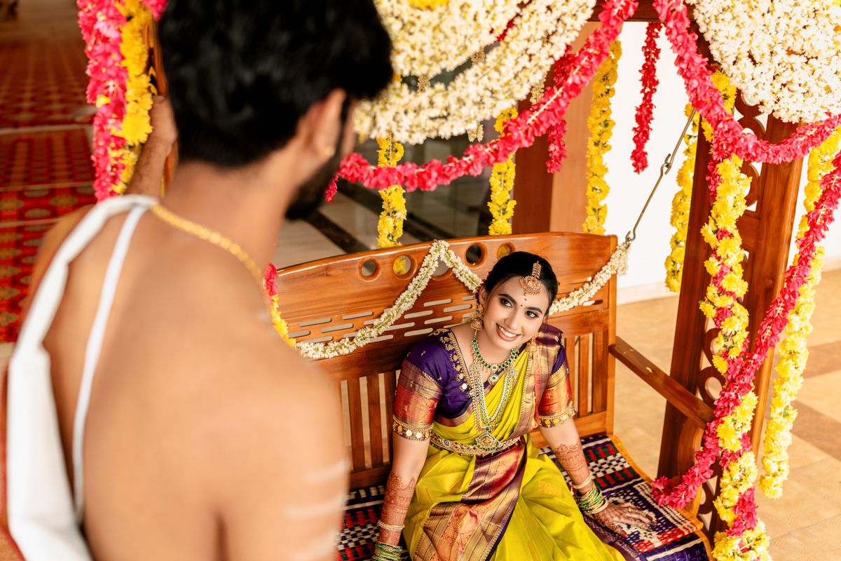 Traditional South Indian wedding ceremony taking place under decorative floral mandap with bright colors.