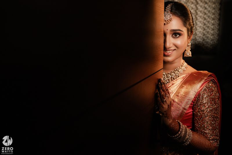 A portrait shows someone wearing traditional South Asian bridal attire with gold jewelry and embroidered maroon dress.