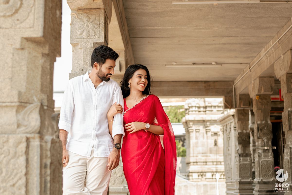 Love story captured in architectural frames with stone pillars and traditional temple backdrop.