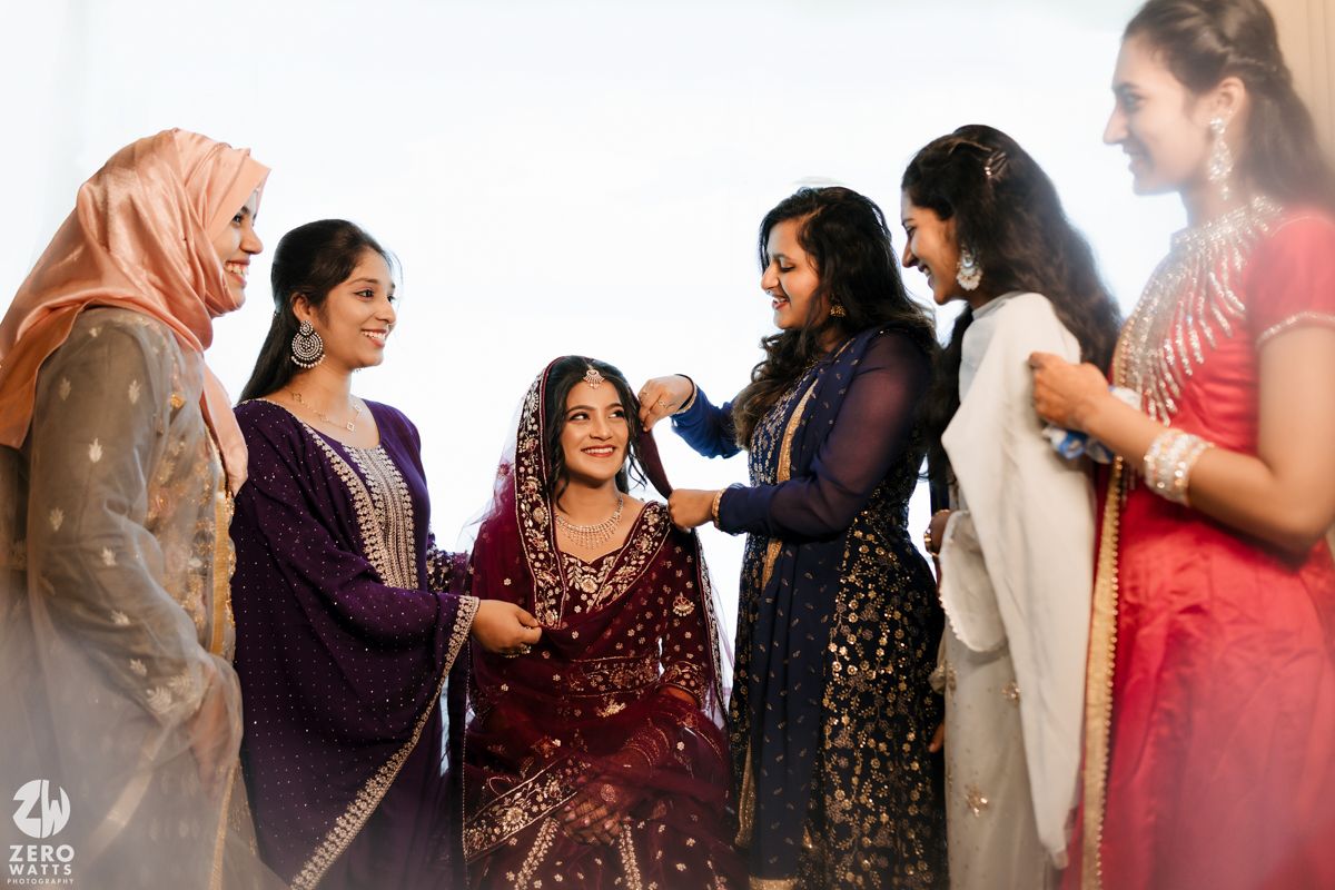 Group of women in colorful traditional attire helping prepare the bride during wedding preparations.