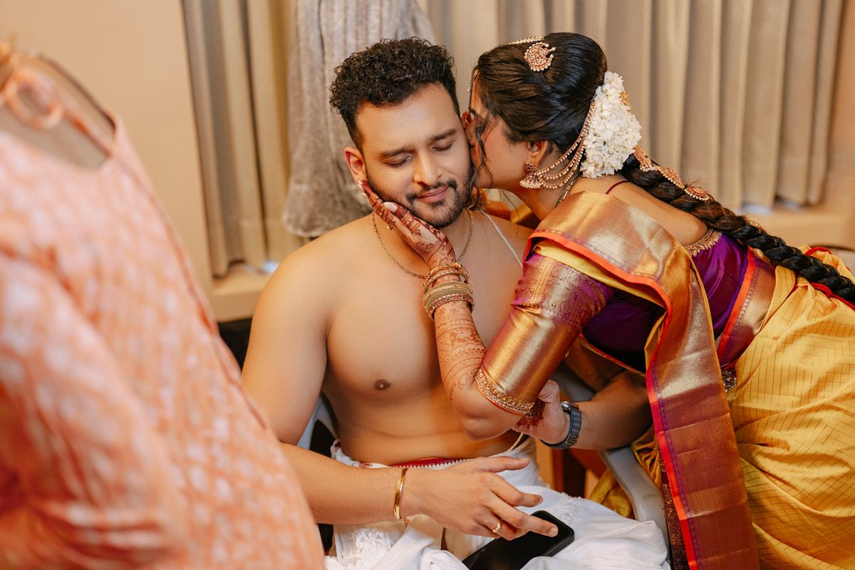 Intimate moment during traditional South Indian wedding ceremony with bride in silk saree and gold jewelry.