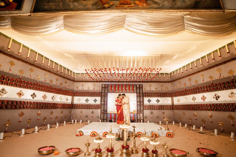 Elegant wedding reception hall decorated with white draping, floral centerpieces and ambient lighting.