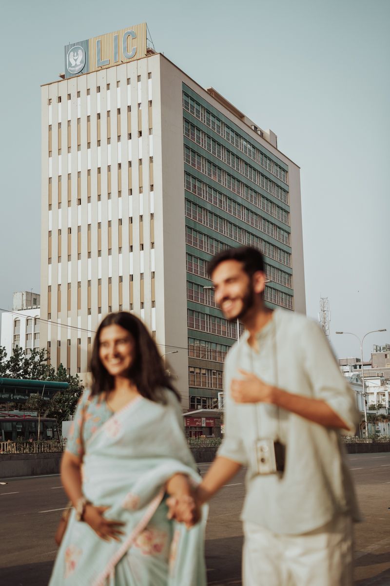 A couple stand in front of a modern office building with LIC signage.