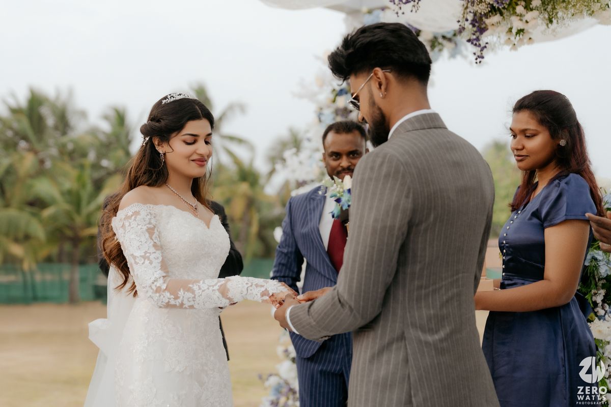 Couple exchanges vows during an outdoor wedding ceremony with palm trees in the background.