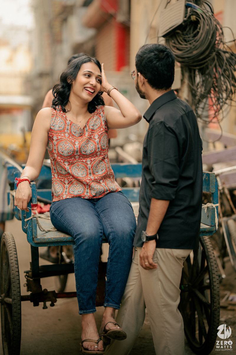A couple shares a candid moment by a rickshaw in an urban street setting.