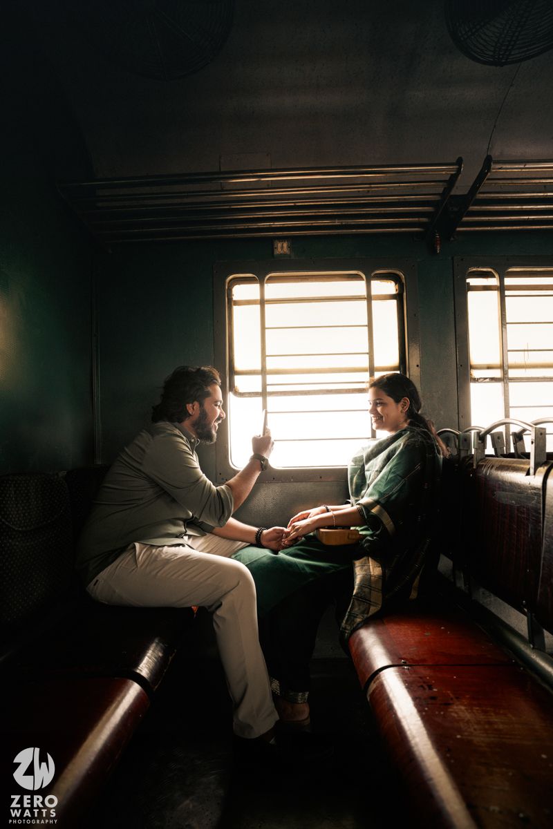 A couple shares an intimate conversation while seated in a vintage train compartment as sunlight streams through the window.
