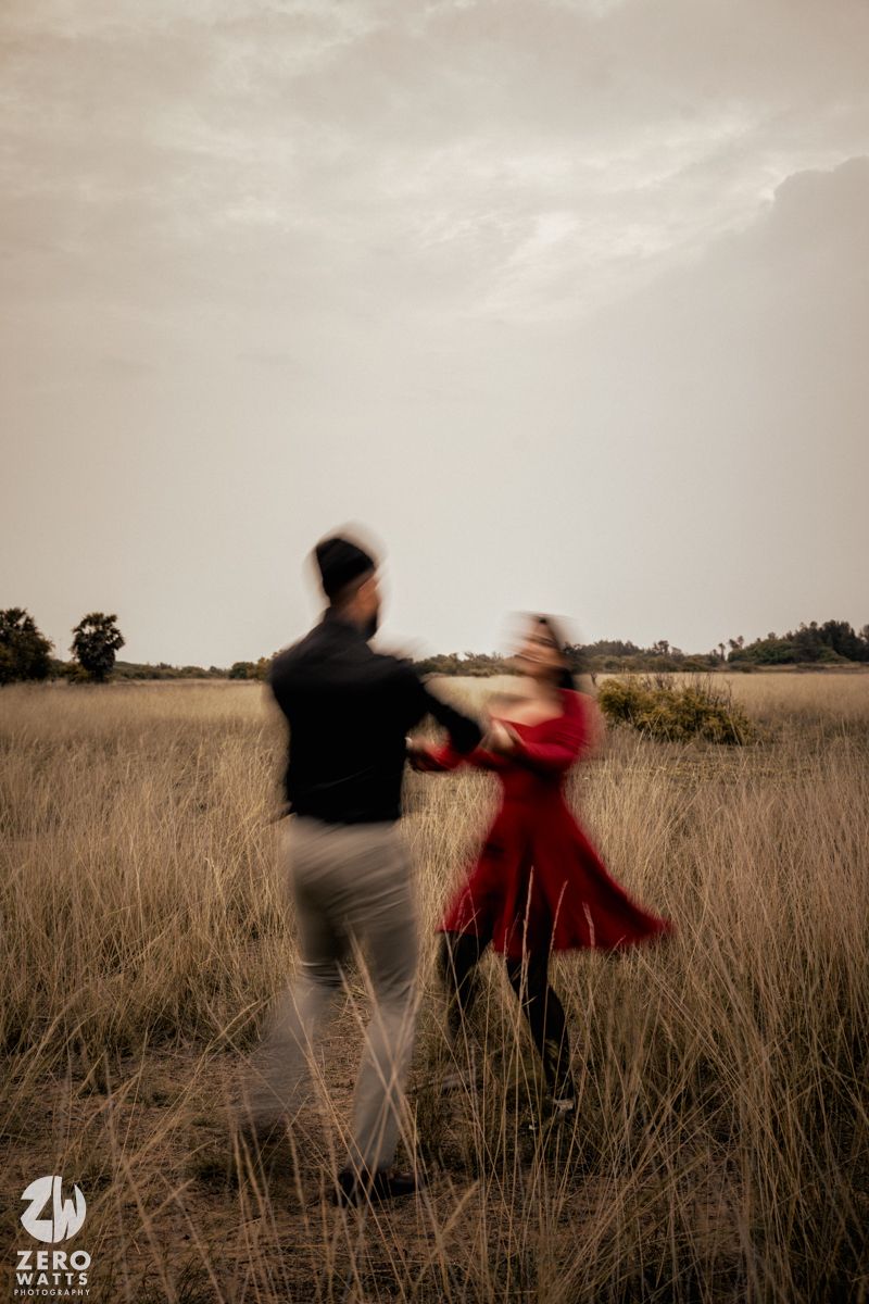 Motion-blurred shot of two people spinning in a field at dusk.