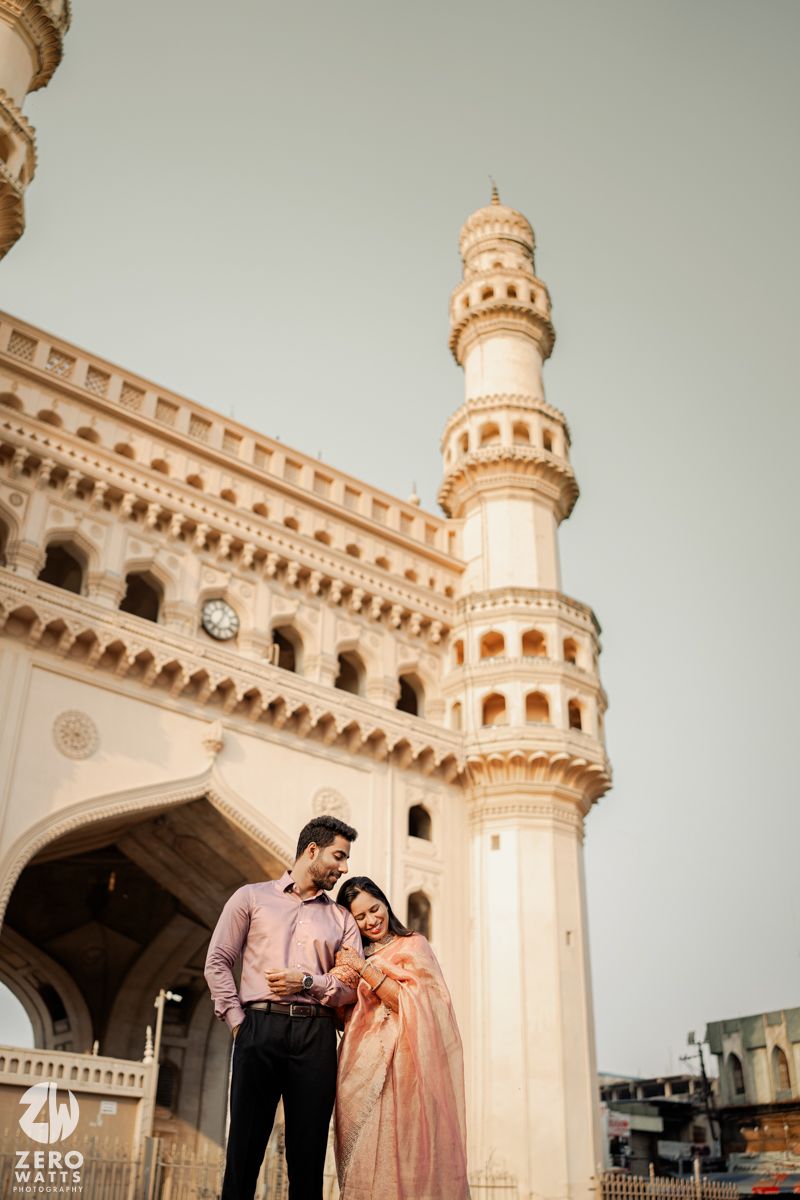 A romantic moment captured in front of a historic mosque with ornate architecture.