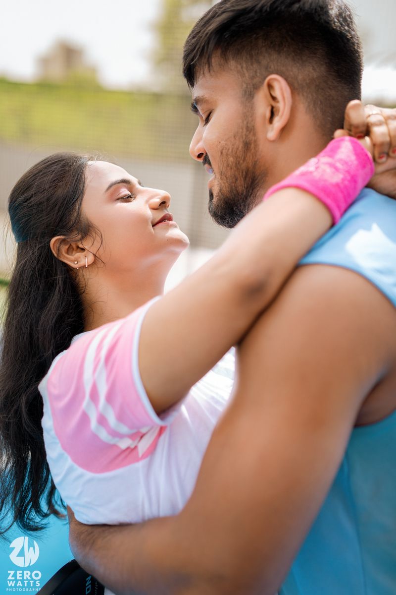 A romantic couple in pink and blue athletic wear sharing an intimate moment on a sports court.