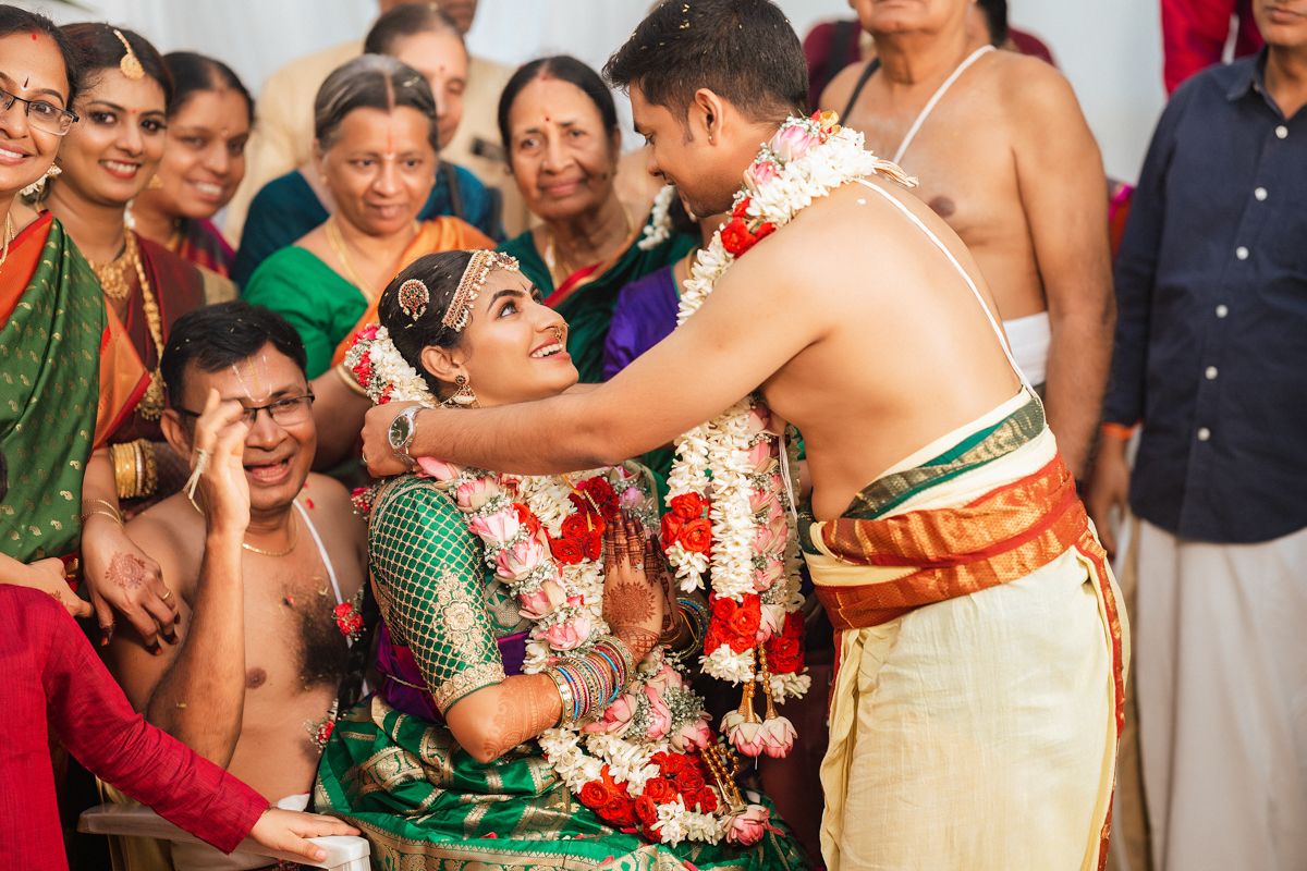 Emotional moment during a traditional South Indian wedding ceremony surrounded by smiling family members.