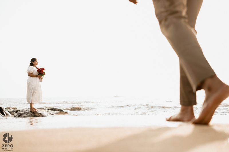 Artistic perspective shot of couple on beach with rocks and ocean waves.