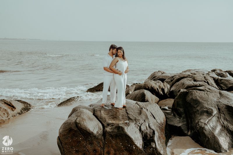 Romantic seaside photoshoot with couple on rocky beach landscape.
