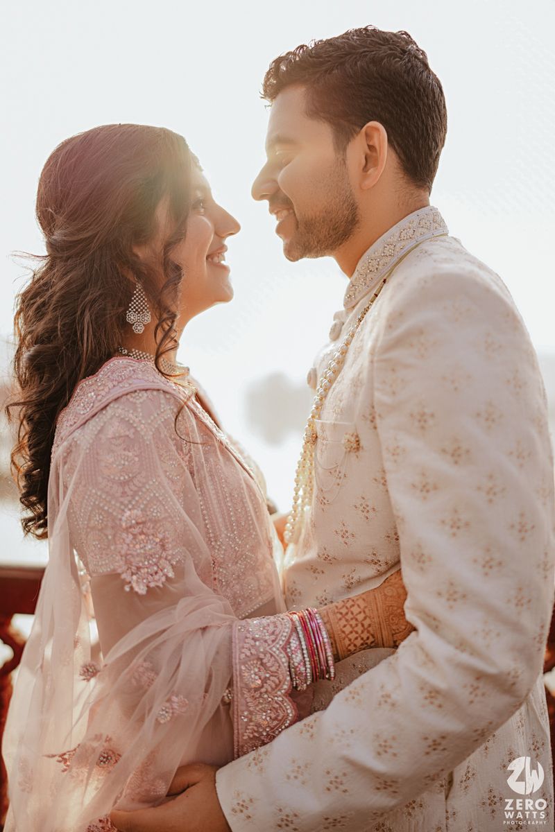 A backlit couple in traditional Indian wedding outfits embrace during their golden hour photoshoot.