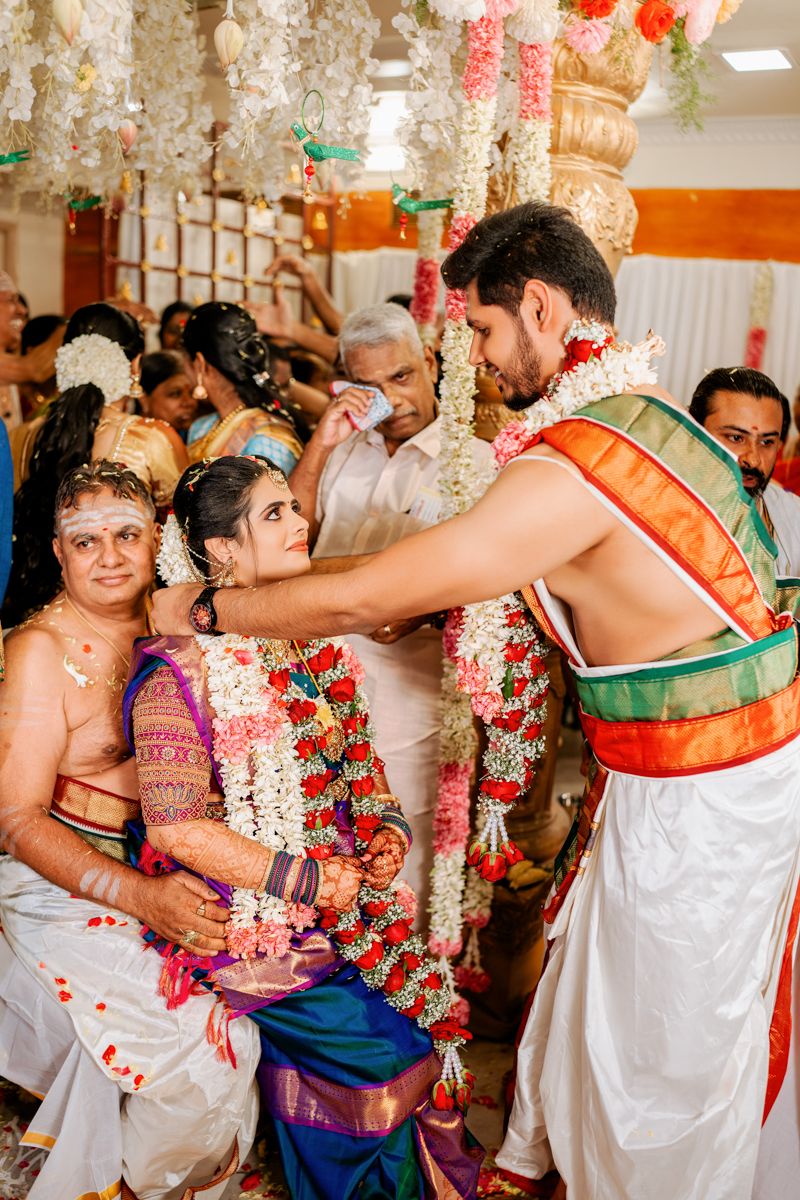 Traditional South Indian wedding ceremony with decorative flower garlands and traditional attire during a ritual.