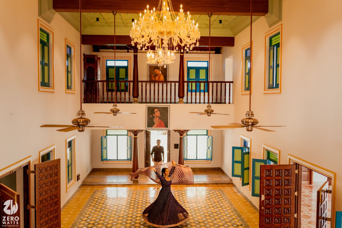 Grand heritage mansion interior features ornate chandelier and traditional tiled floors in Kerala architectural style.