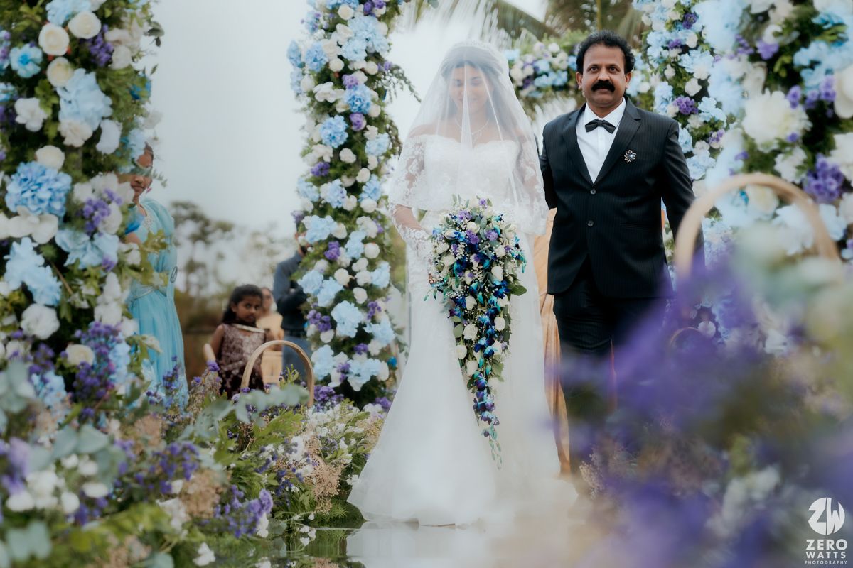 A wedding ceremony under an elegant floral arch decorated with white and purple flowers.