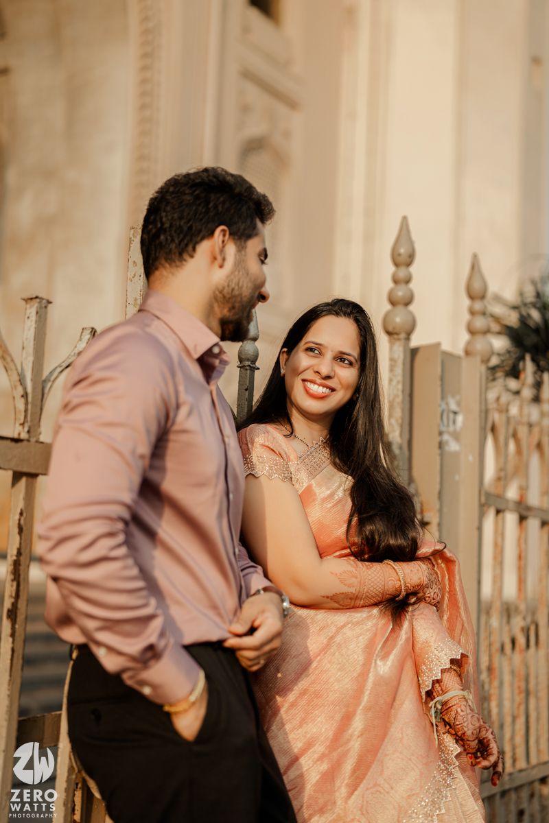 A couple shares a tender moment near decorative architectural elements at sunset.