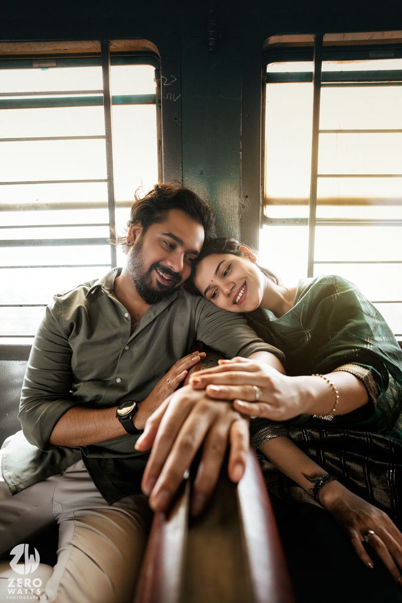 Soft afternoon light streams through windows as a couple relaxes on train car seats.