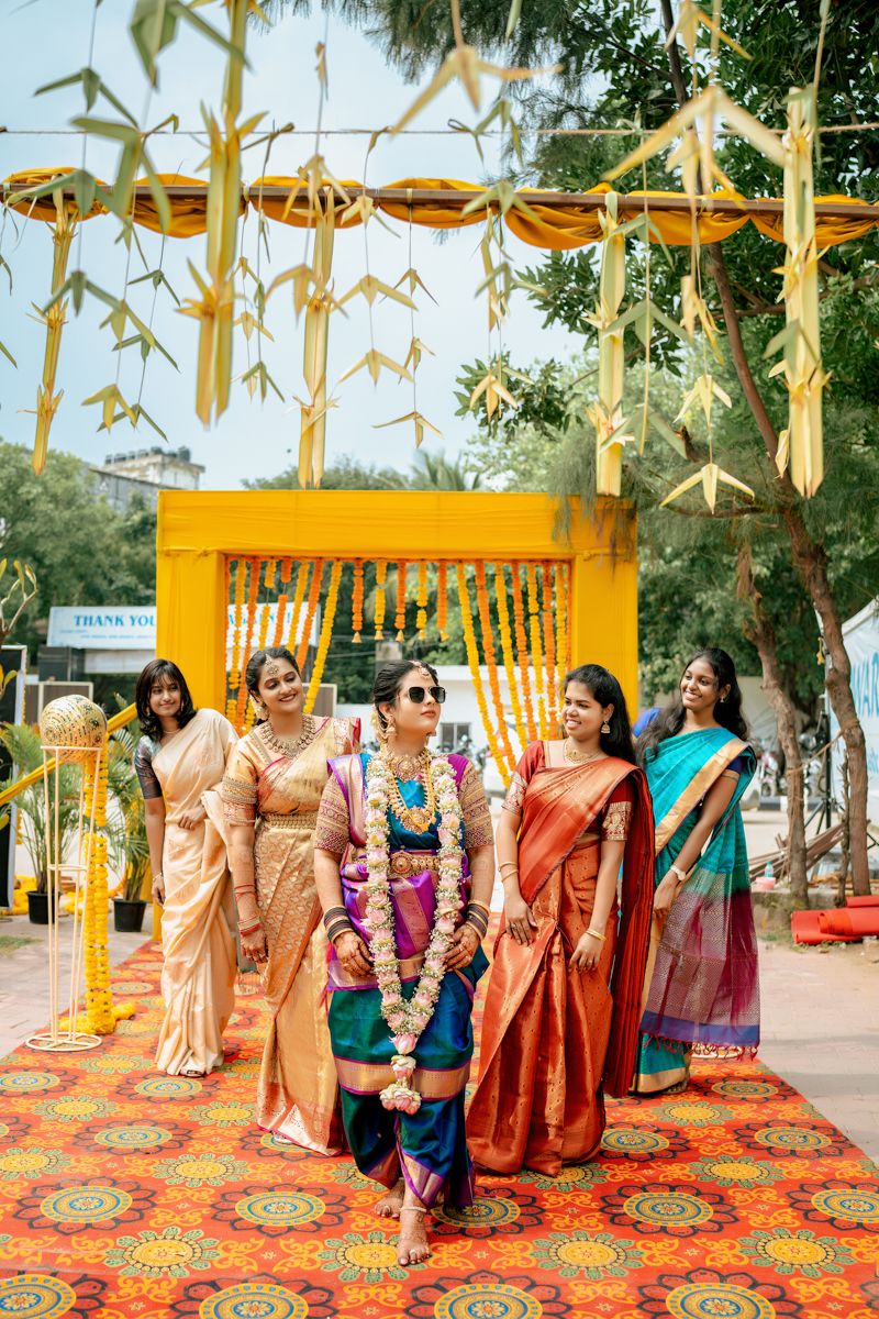 Traditional Indian wedding ceremony with colorful saris and floral decorations under bamboo canopy.