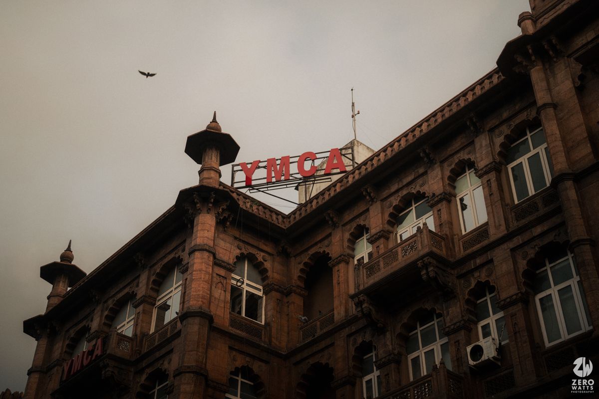 Historic brown building with colonial architecture and domed towers against moody sky.