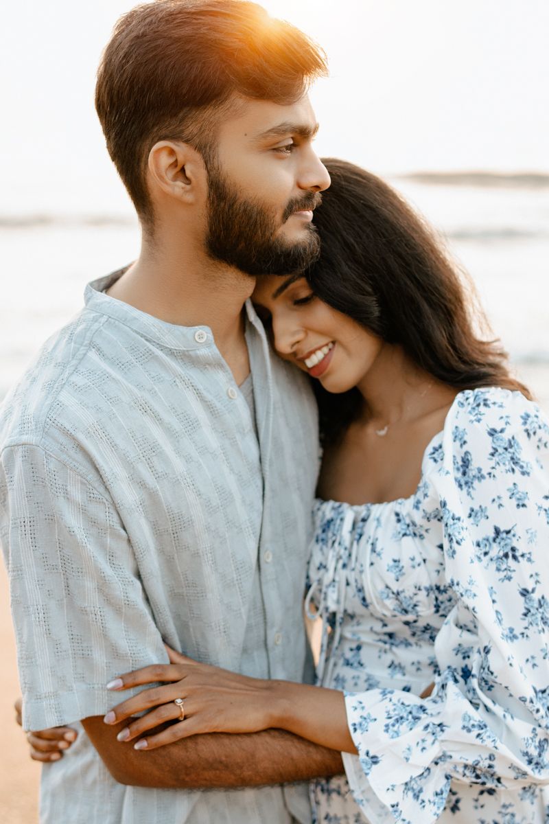 A couple shares an intimate moment at the beach during golden hour.