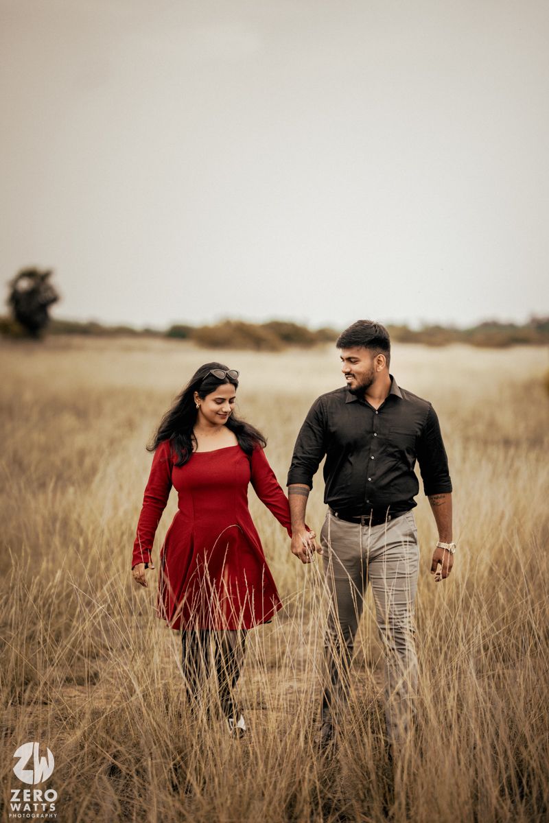 Romantic couple strolling hand in hand through a misty field at dusk.