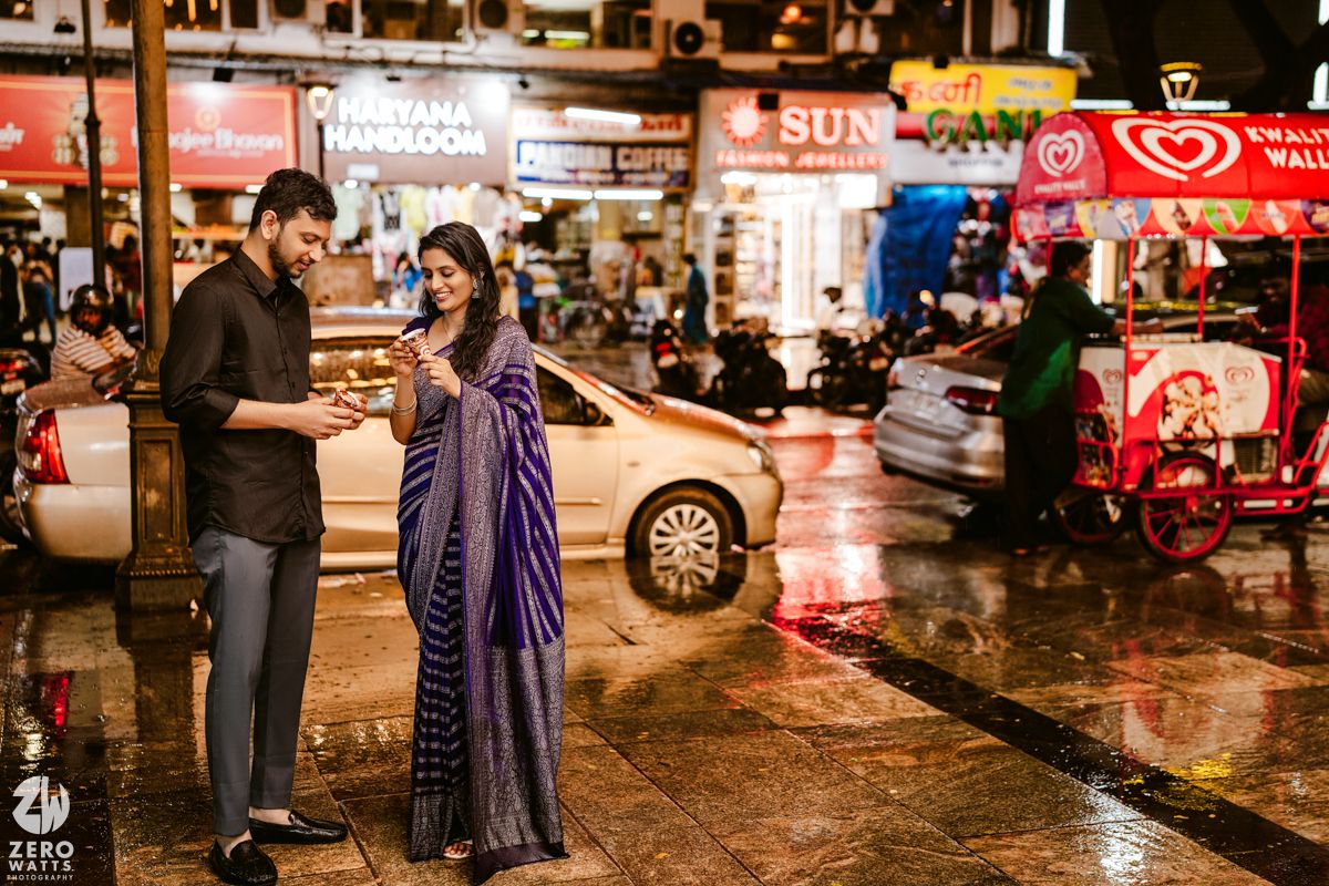 A couple enjoying street food on a rainy evening in an urban setting with neon lights.