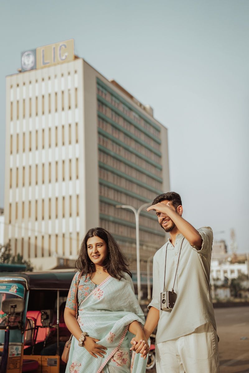 Two people in traditional Indian wear sharing a playful moment in front of a corporate building.